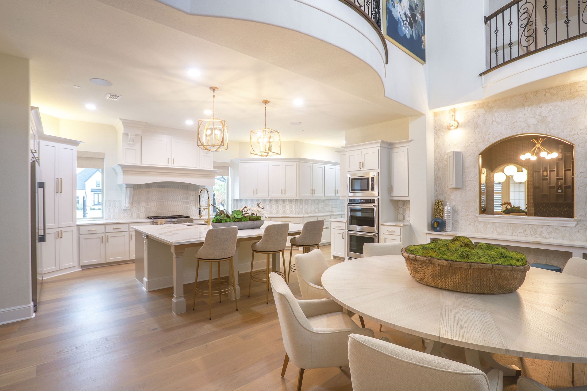 Effortless by Brooke - Decorating Den Interiors open kitchen and dining in two-story home and tall spaces.